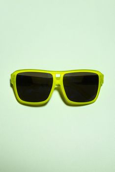 Green bright sunglasses on a pastel background. Summer time, party and vacations concept. Minimalism with sunglasses.