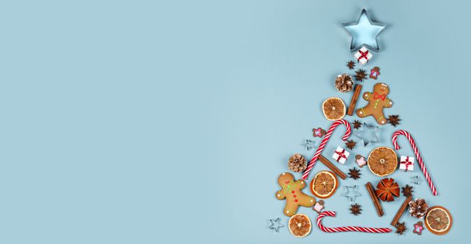 Christmas tree symbol composition. Ginger cookies caramel candy canes mold star form gifts orange and baubles, flat lay with copy space