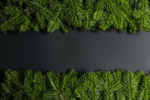 Christmas border arranged with fresh fir branches on black paper background , copy space for text