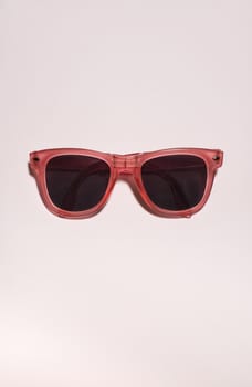 Red bright sunglasses on a pastel pink background. Summer time, party and vacations concept. Minimalism with sunglasses.