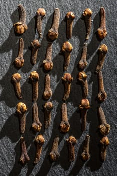 Dried Cloves on dark stone background. Natural hard light. Spice cloves close-up shot. Cooking with aromatic condiments conceptual background.