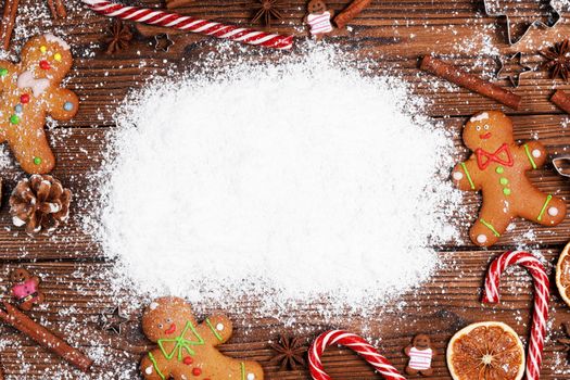 Christmas flat lay background with traditional gingerbread cookies dried orange cinnamon on wood white snow copy space for text