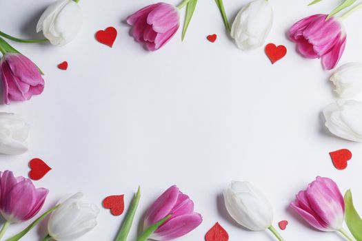 Frame of fresh tulip flowers and decorative hearts isolated on white background