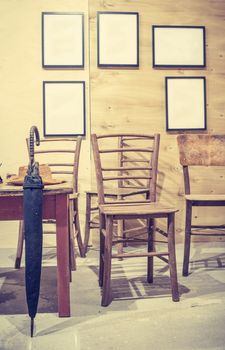 Vintage room interior and furnitures. Old table and chairs, umbrella and hat on the table. Picture frames on vintage wall. Pastel tones. 