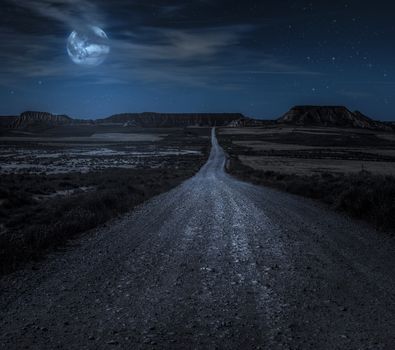 Moon, stars and clouds in the night. Wild west road illuminated from the moon. Moonlight and road background. Dark blue backdrop.