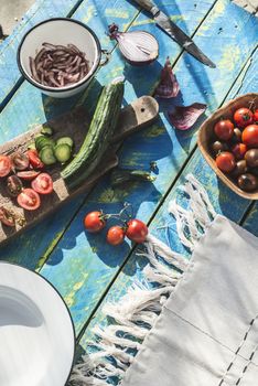 Salad with arugula, Little Gem, cheese, olives, tomatoes, cucumber, onion and caramelized nuts. Concept for healthy food and diet. Natural lighting. Blue wooden vintage table.