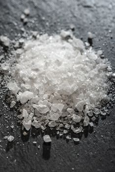 White salt crushed on dark stone background. Close-up Big pieces of salt. Heap pouder salt and natural light.