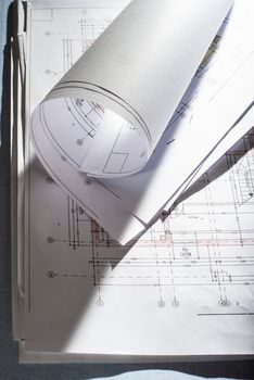 Blueprints on architect desk. Stacked and rolled up architectural projects on natural window light. Construction and building concept.