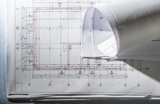 Blueprints on architect desk. Stacked and rolled up architectural projects on natural window light. Construction and building concept.