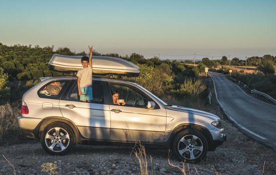 Little boy show up on car window. Tourist car on the road. Travel concept with child.