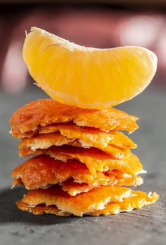 Stack of mandarin peel and a tangerine on top. Close-up shot of citrus fruits. Authentic light.