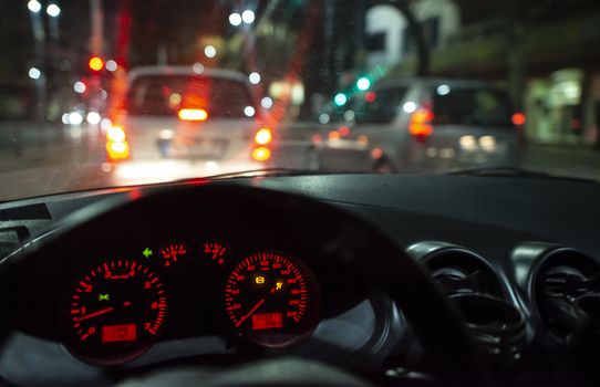 Car dashboard and window at night. Traffic lights