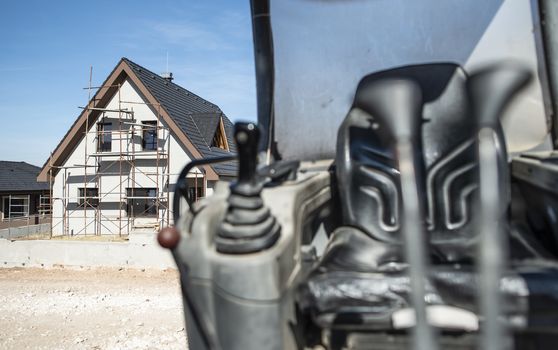 Excavator and newly built houses on construction site