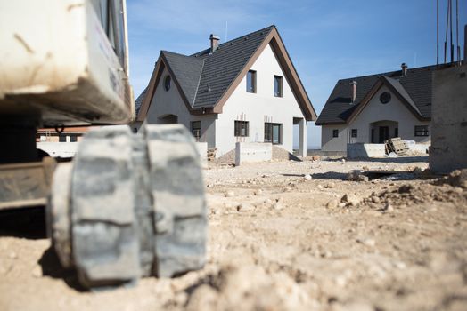 Excavator and newly built houses on construction site