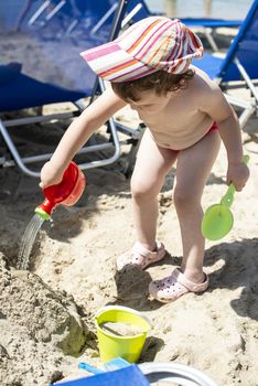 Little girl play with water on the beach. 