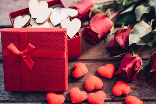 Red hearts, flower roses and gift box on wooden background, valentine day concept