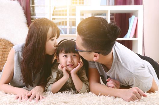 Asian parent kissing their daughter at home