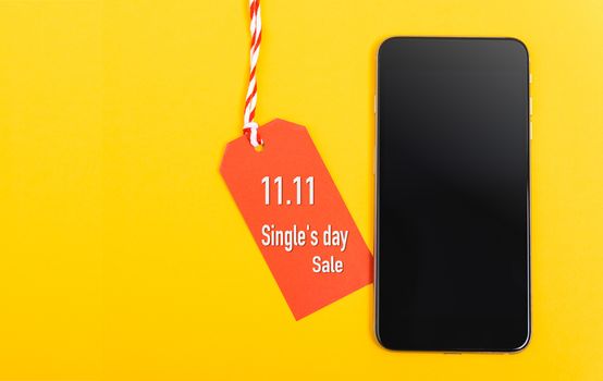 11.11, Online shopping Single's day sale text red tag label and smart phone blank screen, with copy space on yellow background