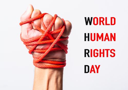 Red rope on fist hand with WORLD HUMAN RIGHTS DAY text on white background, Human rights day concept