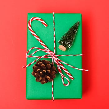 New Year, Christmas Xmas holiday composition, Top view gift green box, clews of rope and green fir tree branch on red background with copy space