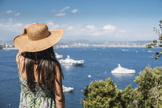 Woman with summer hat watching yachts. French riviera