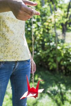  Woman hold red origami crane in the garden