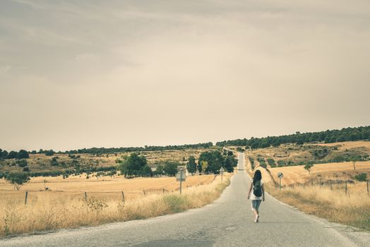 Woman with backpack walking on the road