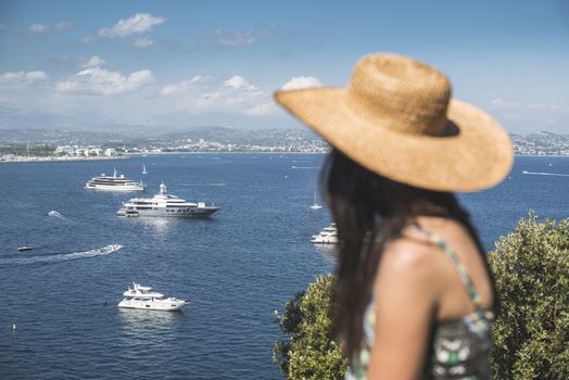 Woman with summer hat watching yachts. French riviera