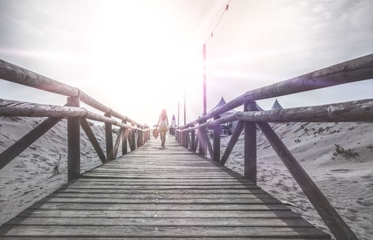 Woman with hat on wooden trail on the beach in the morning. Sunrise