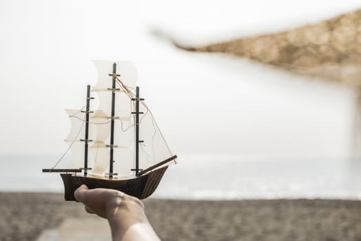 Woman with hat hold boat model on the beach