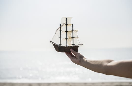 Woman with hat hold boat model on the beach