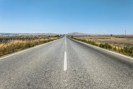 Long asphalt road and blue sky.