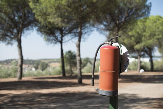 Fire extinguisher in the woods. Trees on the background