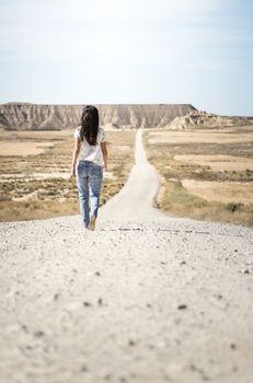 Woman walking on dirt road. Looking like a movie
