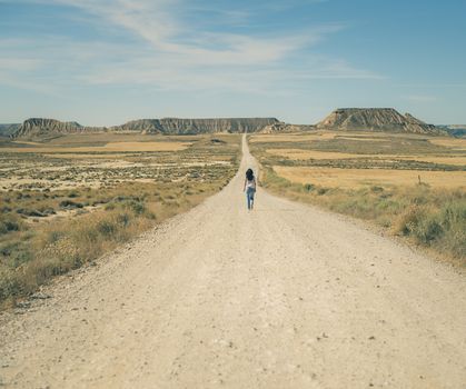 Woman walking on dirt road. Looking like a movie