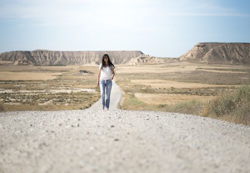 Woman walking on dirt road. Looking like a movie