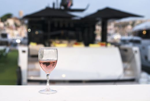 Glass of rose wine and a yacht on the background