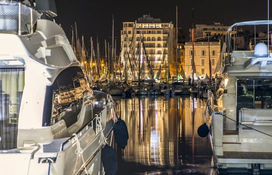 Yachts in the cannes bay at night.  Illuminated buildings 