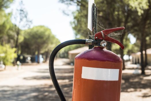 Fire extinguisher in the woods. Trees on the background