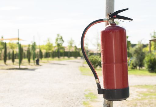 Fire extinguisher in the woods. Trees on the background