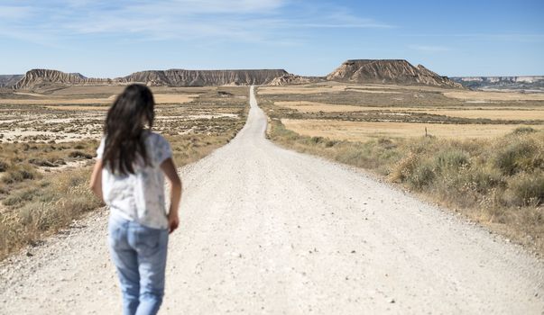 Woman with jeans walking on wild west dirt road