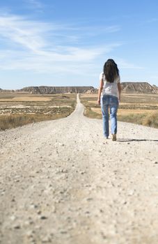 Woman with jeans walking on wild west dirt road