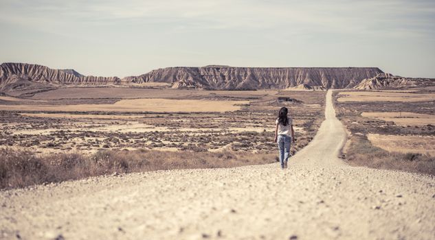 Woman walking on dirt road. Looking like a movie