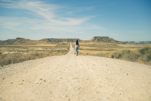 Woman walking on dirt road. Looking like a movie