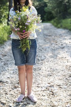 Woman hold bouquet of wildflowers in the forest.