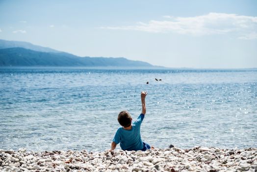 Children throw stones at the water of the sea. 