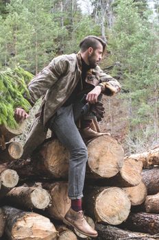 Young men on logs in the forest. Leather and jeans. Outdoor fashion