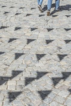 Shadows of festival flags. People wlak on paved road