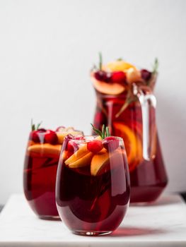 Winter sangria on tabletop. Glasses of sangria with fruit slice, cranberry and rosemary. Vertical. Copy space for text or design.