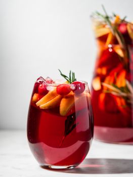 Winter sangria on tabletop. Glasses of sangria with fruit slice, cranberry and rosemary. Vertical. Copy space for text or design.